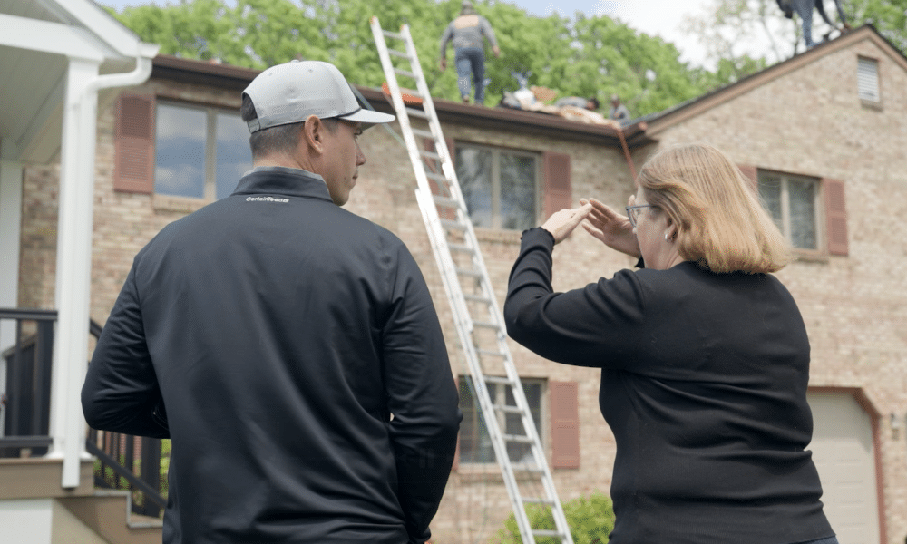 Joel Keefer from Roof Duck talking to a homeowner while her roof is being replaced in the background